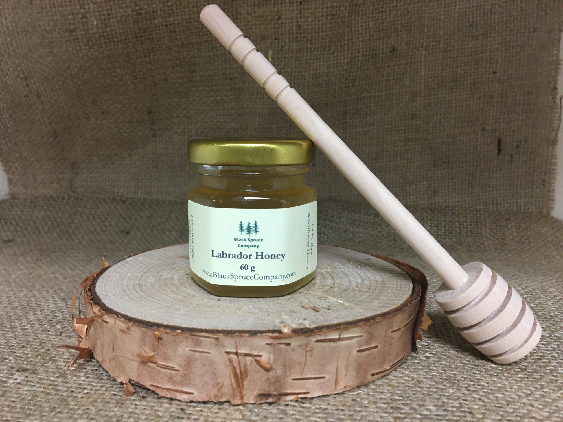 Medium sized wooden honey dipper with small jar of honey